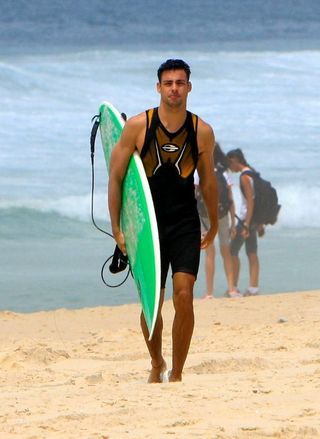 Cauã Reymond pratica surfe em praia carioca