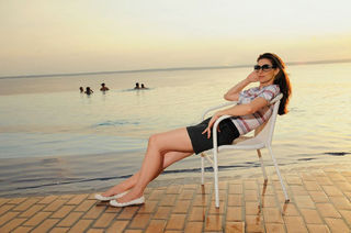 Ela relaxa e curte o pôr-do-sol à beira da piscina às margens do Rio Negro.