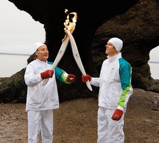 Militar veterano, Keith Steeves acende a tocha que Cielo segura em Hopewell Rocks.