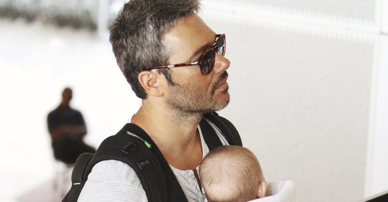 Ângelo Leme carrega o filho no aeroporto