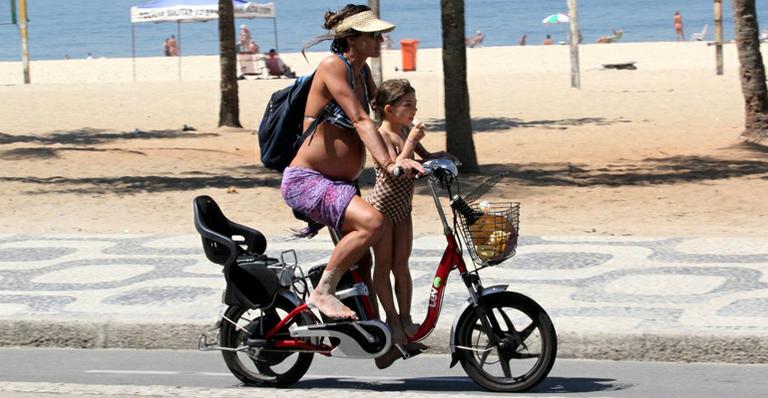 Com barrigão, Cynthia Howlett passeia de bicicleta com a filha em Ipanema