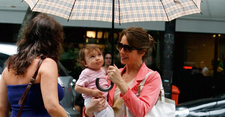 Letícia Spiller protege a filha da chuva