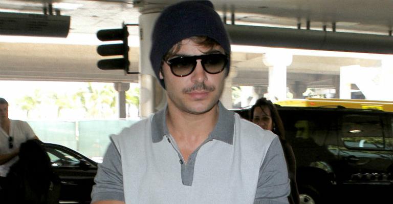 Zac Efron exibe bigode em aeroporto de Los Angeles