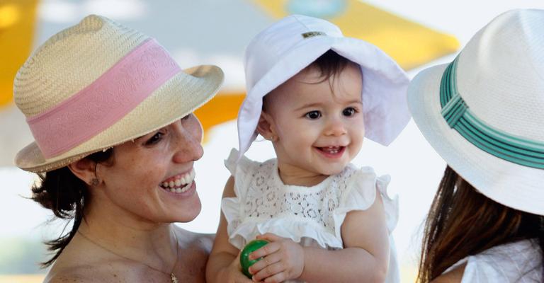 De chapéus, Fernanda Pontes e a filha passeiam pela orla do Rio