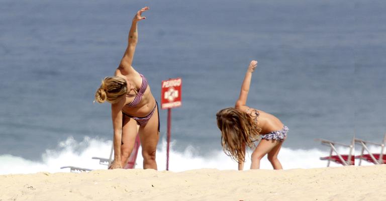 Amora Mautner se exercita com a filha na praia do Leblon