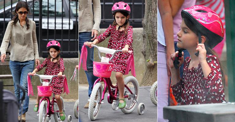 Suri Cruise passeia em bicicleta rosa com rodinhas sob olhar atento de Katie Holmes