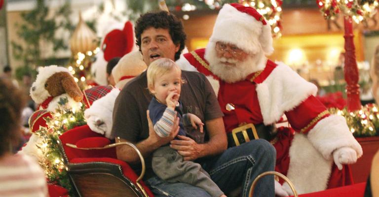 Felipe Camargo leva o filho para sentar no trenó do Papai Noel