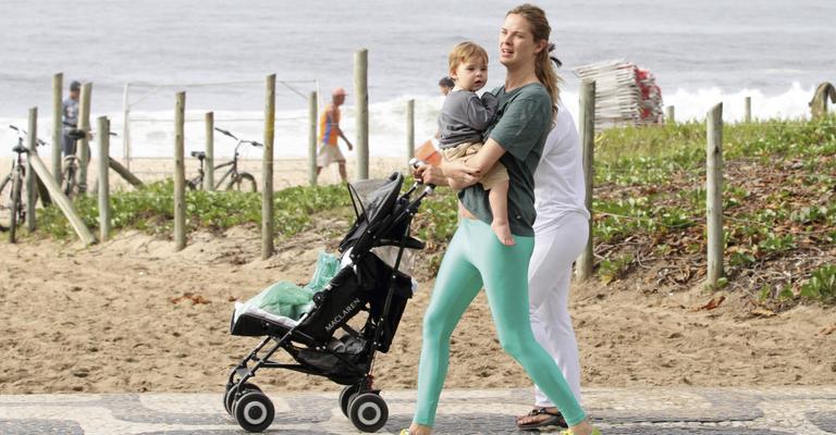 Letícia Birkheuer se exercita na orla da praia com o filho no colo