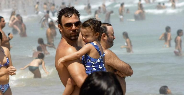Marcelo Faria curte praia e protege a filha do sol