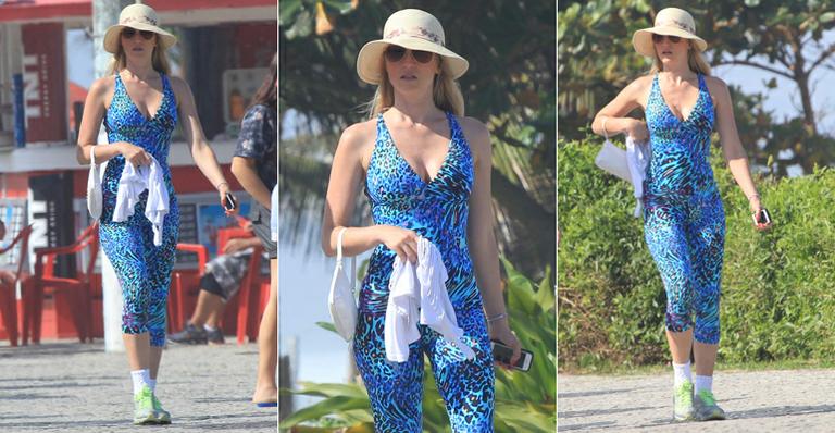 De macacão, Susana Werner caminha na orla da Barra, no Rio de Janeiro