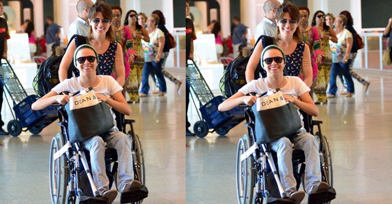 Maria Gadú e sua mulher aparecem sorridentes em aeroporto