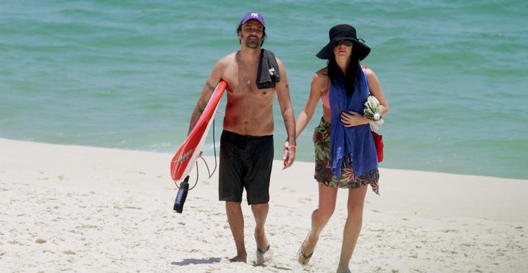 Alinne Moraes esconde sua barriga de cinco meses na praia da Reserva no Rio