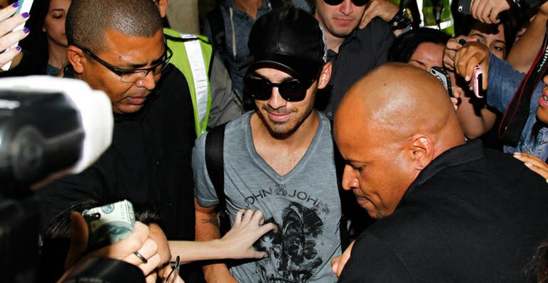 Joe Jonas chega ao Brasil e é rodeado por fãs no aeroporto
