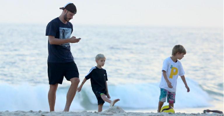 Rodrigo Hilbert joga bola com os filhos na praia
