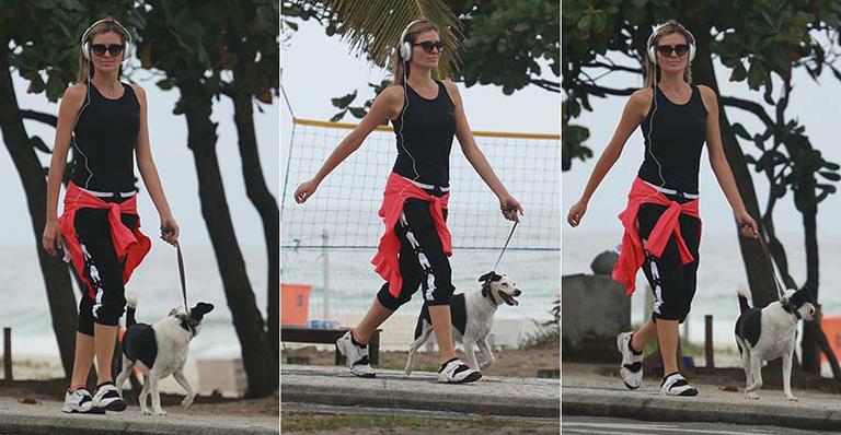 Ellen Jabour caminha com seu cachorro na orla da praia da Barra da Tijuca