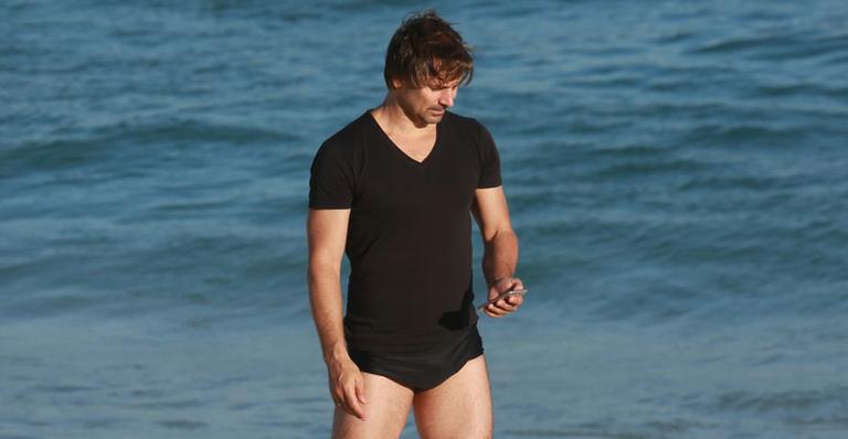 Sem desgrudar do celular, Murilo Rosa curte dia de praia no Rio de Janeiro