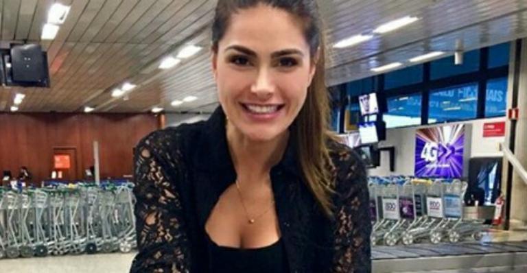 Natalia Guimarães posa sorridente com as filhas gêmeas em aeroporto