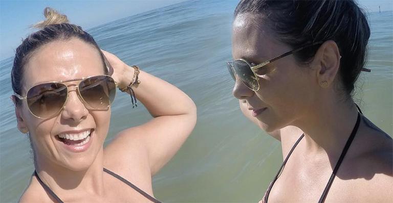 Aos 38, Carla Perez mostra barriga definida na praia com Xanddy