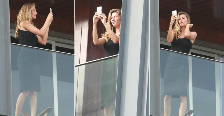 No Brasil, Gisele Bündchen aparece em sacada de hotel em busca da selfie perfeita