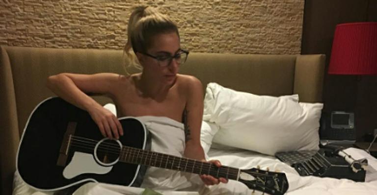 Nua? Lady Gaga toca violão na cama enrolada em lençol