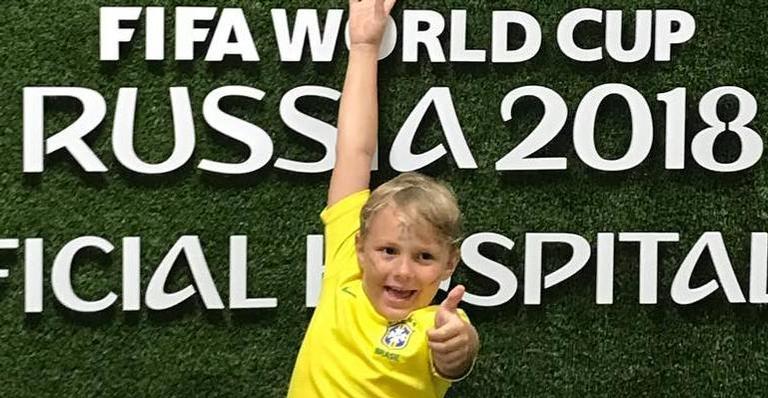 Com tablet gigantesco em mãos, Davi Lucca posa vestido de Brasil ao lado da família