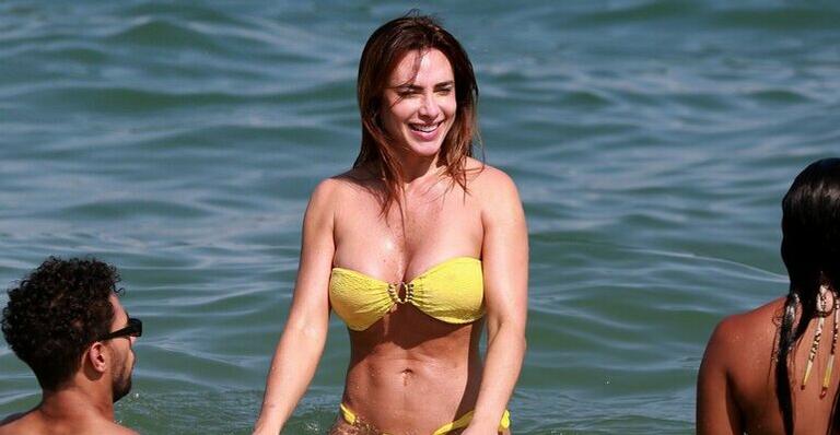 De biquíni fio dental amarelo, Nicole Bahls é flagrada na praia mostrando o bumbum