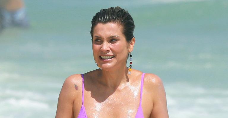 Flávia Alessandra é flagrada na praia e exibe corpo sarado