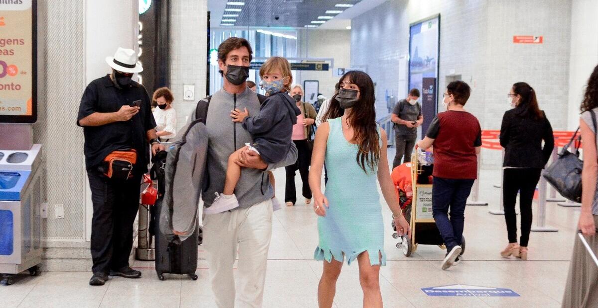 De chinelos, Isis Valverde desembarca com o filho e o marido após férias em Noronha